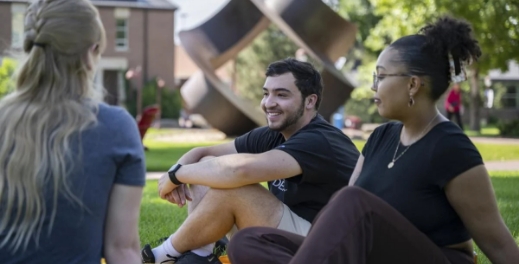 Three students sitting outside talking